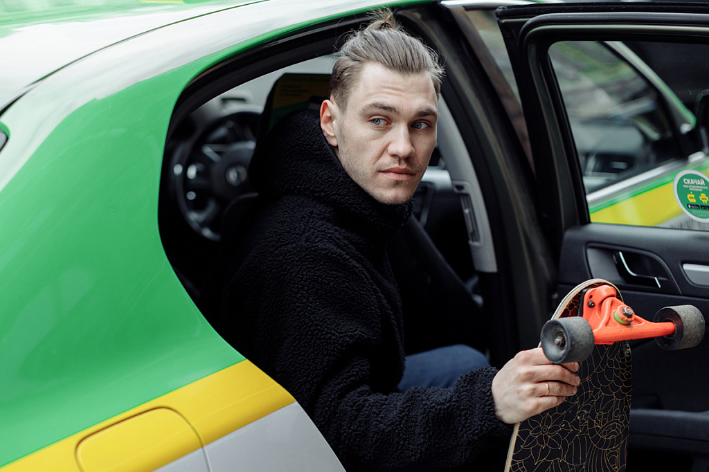 Мужчина со скейтбордом в такси Таксовичкоф